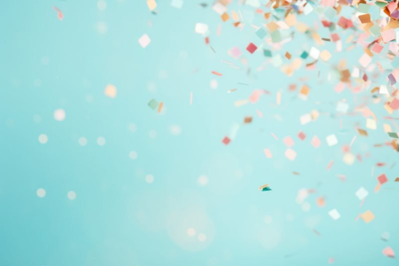 Bright confetti falling against a soft party backdrop