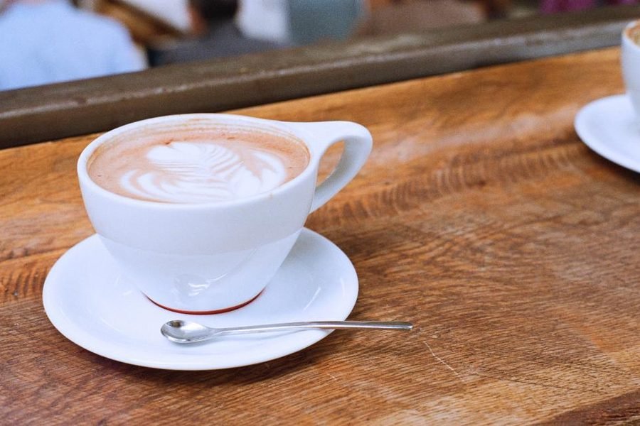 A latte with poured art on a wooden cafe table