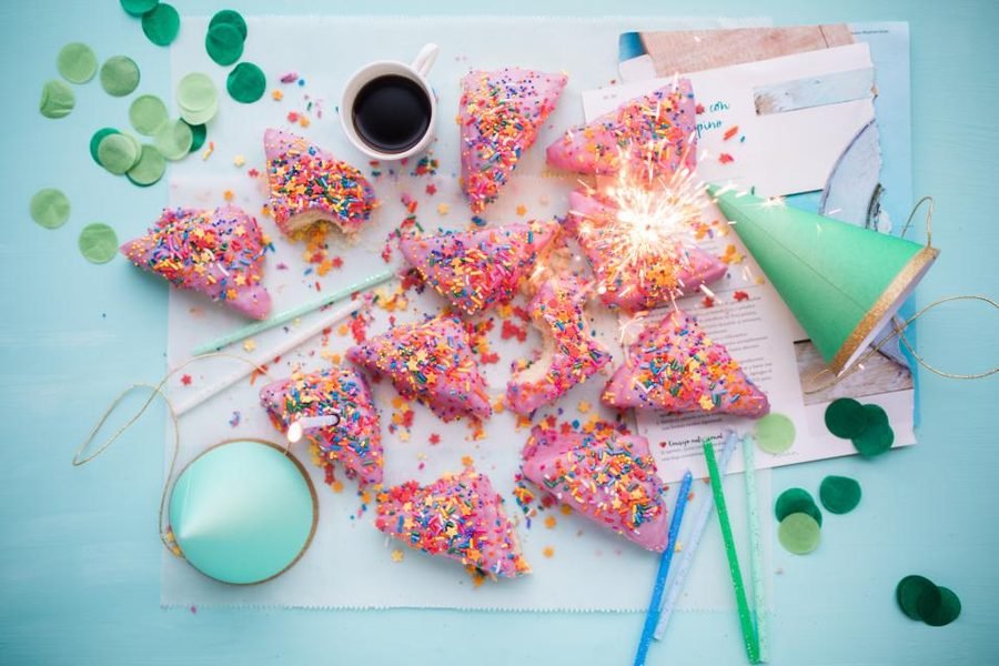 Pink sprinkled treats and confetti on a mint dessert table